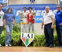 dos atletas de taekwondo mostrando los trofeos junto a cuatro entrenadores