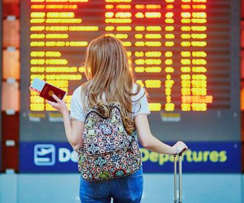 student looking at a travel airport flight monitor