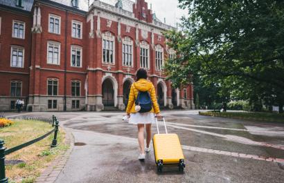 student pushing luggage in front of a student dorm