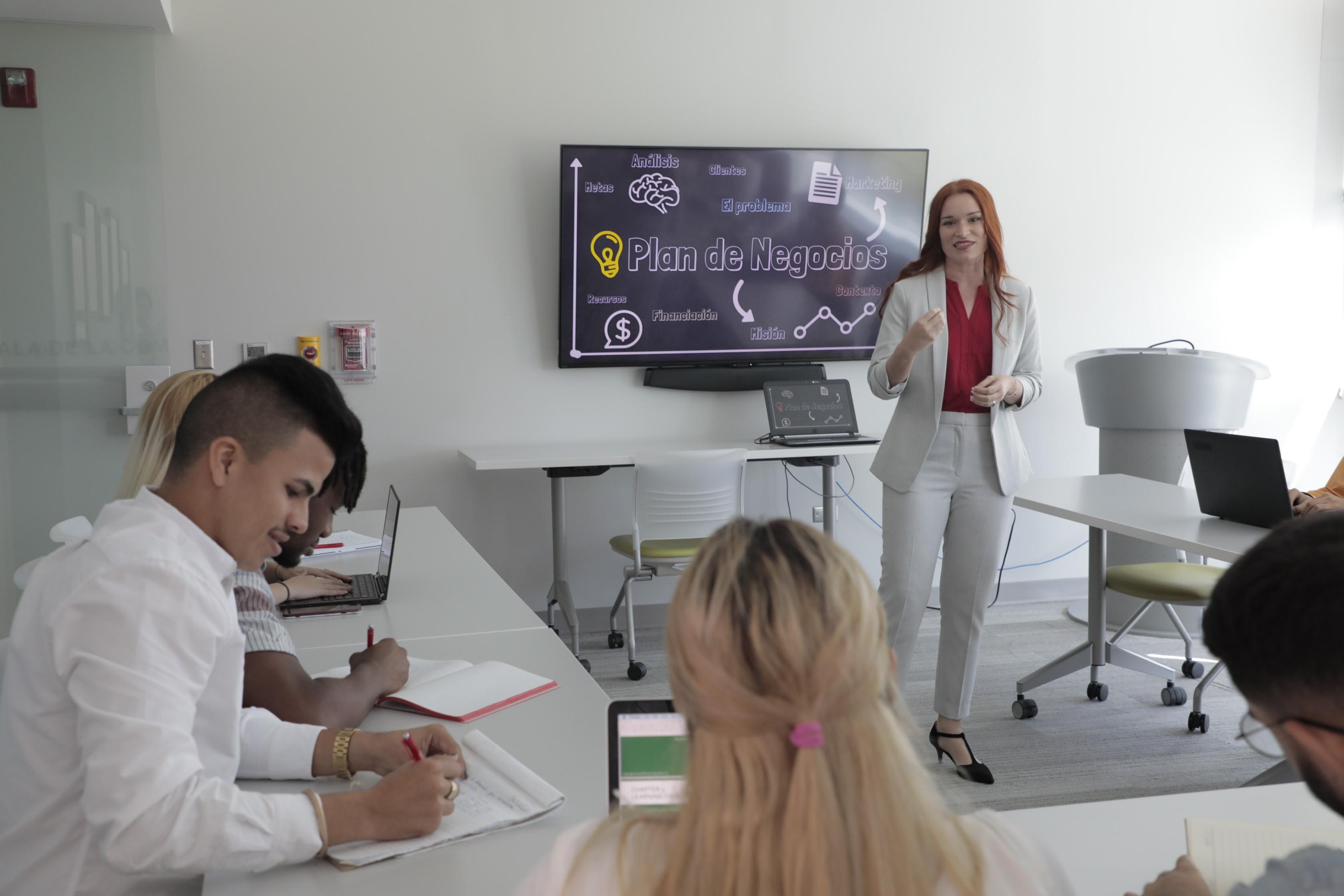 estudiantes reunidos en un salon de clases con profesora