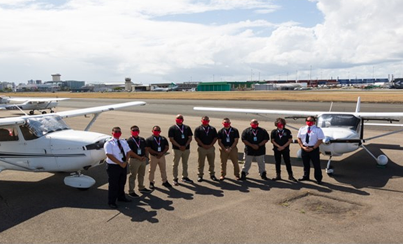 grupo de estudiantes pilotos y dos avionetas