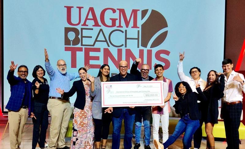 grupo de facultad y estudiantes celebrando con cheque de la actividad de UAGM Beach Tennis Open